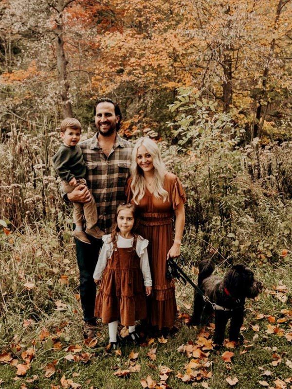 Dr. Berhard and family standing surrounded by fall leaves